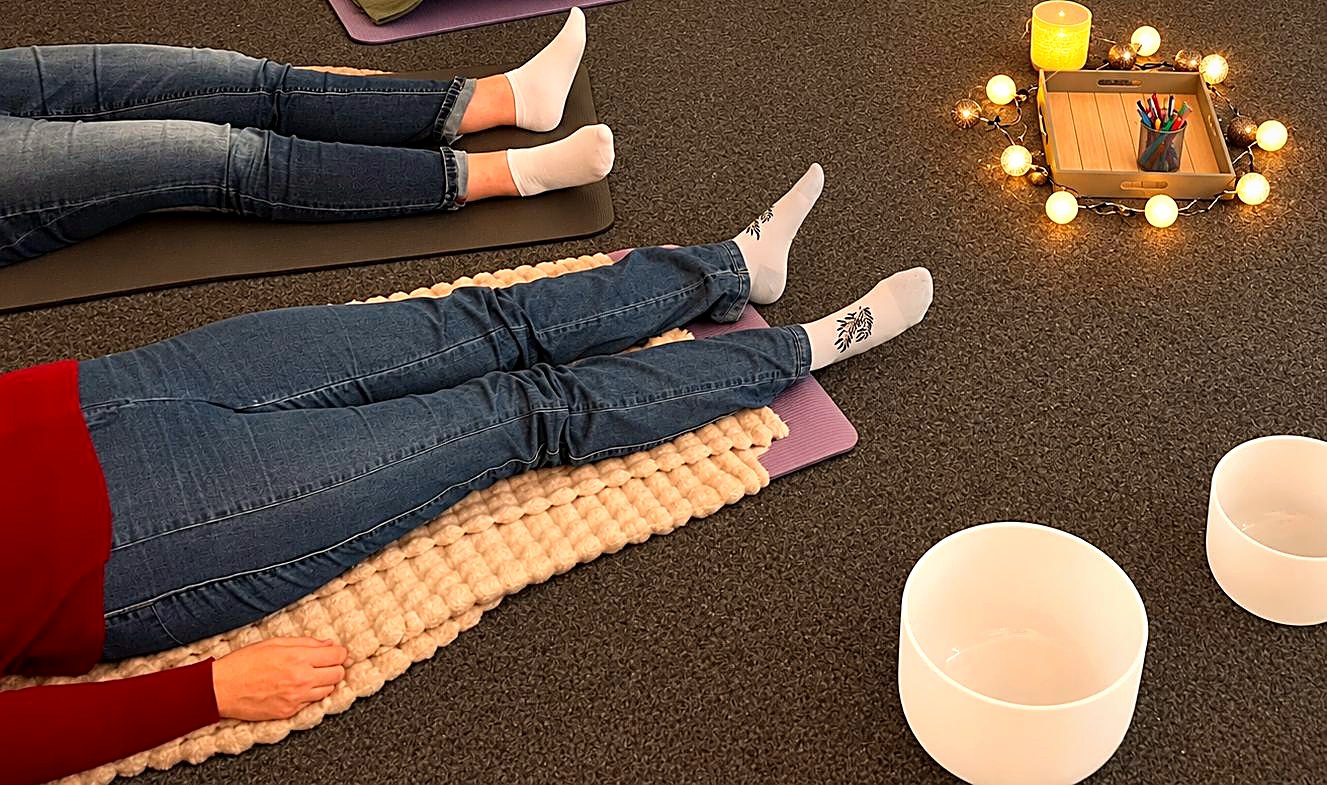 Gesundheitstag – Mitarbeitende beim Entspannungsworkshop Mitarbeitende entspannen auf Matten bei einem Workshop zur Stressbewältigung, mit Kerzenlicht und Klangschalen