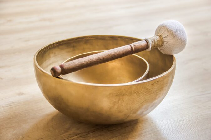 Klangschale mit Klöppel Zwei ineinandergestellte Klangschalen mit Filzklöppel auf einem hellen Holzboden